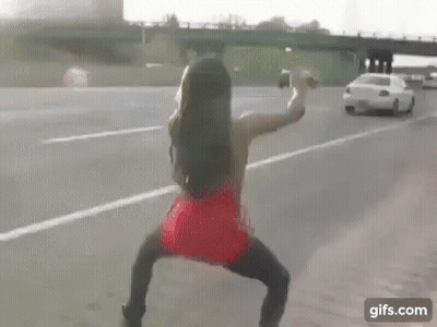 Woman In Red Dress Walking Across Highway GIF
