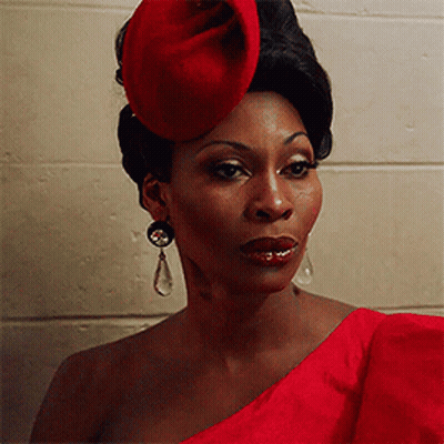 Woman In Red Hat And Earrings In Front Of Brick Wall GIF