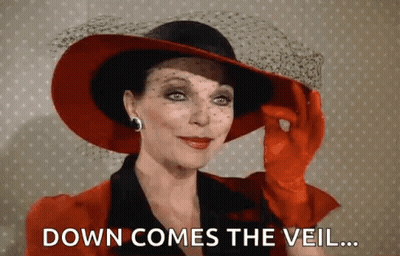 Woman In Red Hat And Gloves Says Down Comes The Veil GIF