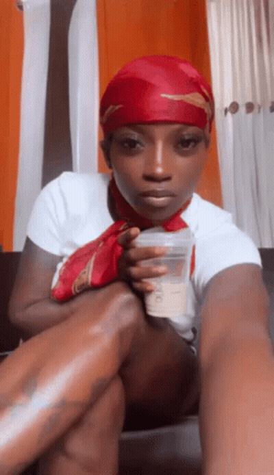 Woman In Red Head Scarf Sitting On Couch Holding Cup GIF