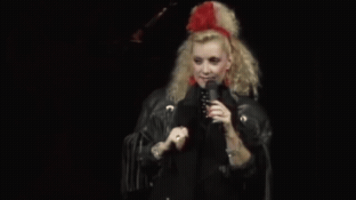 Woman In Red Headband And Black Jacket Singing Into Microphone GIF