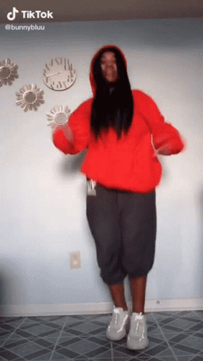 Woman In Red Hoodie Dancing In Front Of Clock Wall GIF