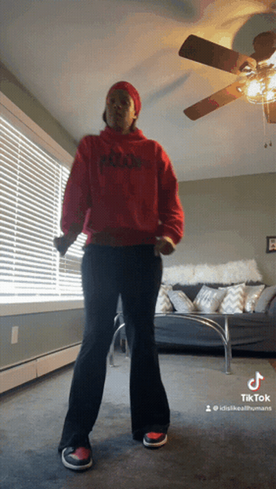 Woman In Red Hoodie Dancing In Living Room With Ceiling Fan GIF