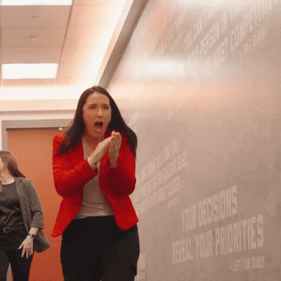 Woman In Red Jacket Clapping In Front Of Wall Saying Your Decisions Reveal Your Priorities GIF