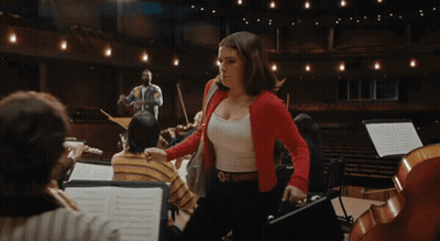 Woman In Red Jacket In Front Of Orchestra GIF