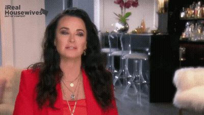 Woman In Red Jacket In Front Of Real Housewives Out Of Context Sign GIF