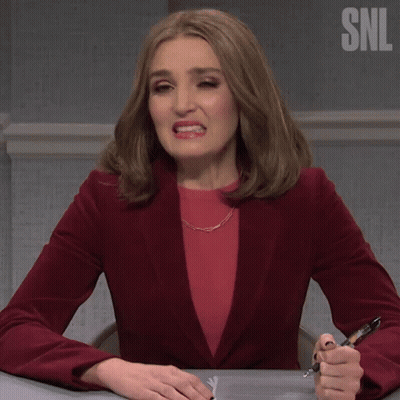 Woman In Red Jacket Sitting At Desk With Pen Saying Oof GIF