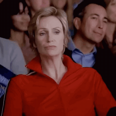 Woman In Red Jacket Sitting In Crowd GIF