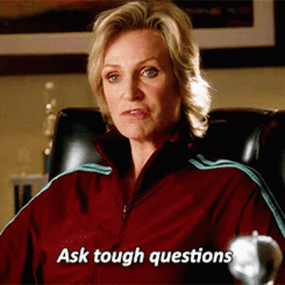 Woman In Red Jacket Sitting With Text Ask Tough Questions GIF