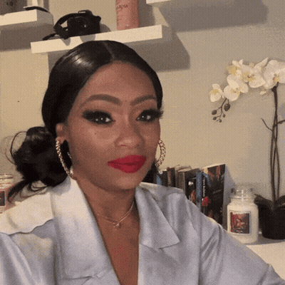 Woman In Red Lipstick And Hoop Earrings Sitting By Candle GIF