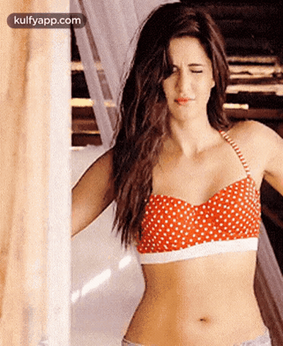 Woman In Red Polka Dot Bikini Top Standing Next To Wall GIF