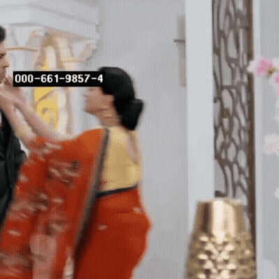 Woman In Red Saree Next To Man In Black Suit GIF