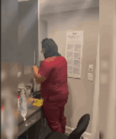 Woman In Red Scrub Top Standing In Front Of Mirror GIF