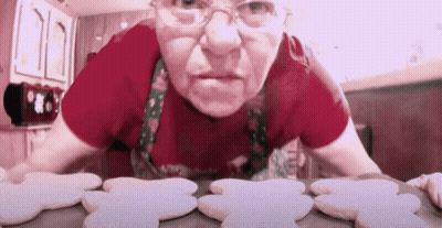 Woman In Red Shirt And Apron Looking At Gingerbread Cookies GIF