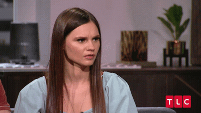 Woman In Red Shirt And Pink Hat In Front Of Chilli Sign GIF
