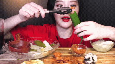 Woman In Red Shirt Eating Pickle With Tongs GIF