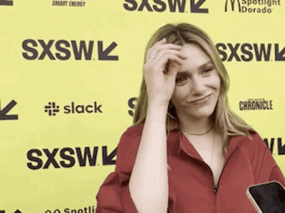 Woman In Red Shirt Holding Cell Phone Adjusting Hair GIF
