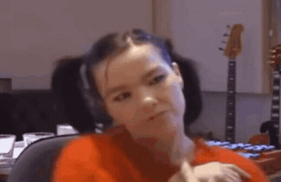 Woman In Red Shirt Sitting In Front Of Guitar GIF