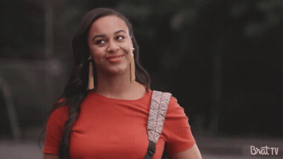 Woman In Red Shirt Smiling With Brat TV Backpack GIF