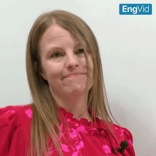 Woman In Red Shirt With Microphone In Front Of Engvid Board GIF