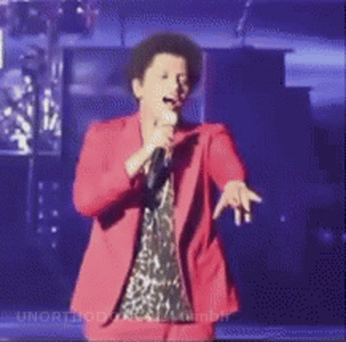 Woman In Red Suit Singing Into Microphone On Stage GIF