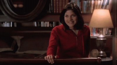 Woman In Red Sweatshirt Smiling In Room With Lamp GIF