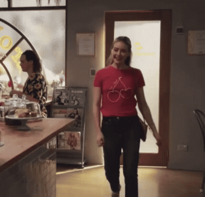 Woman In Red T-Shirt With Cherries Walking Through Restaurant GIF