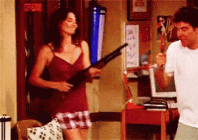 Woman In Red Tank Top Holding Shotgun Next To Man GIF