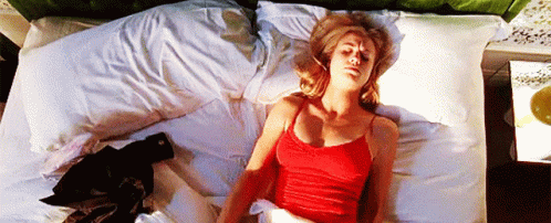 Woman In Red Tank Top Laying On White Bed GIF
