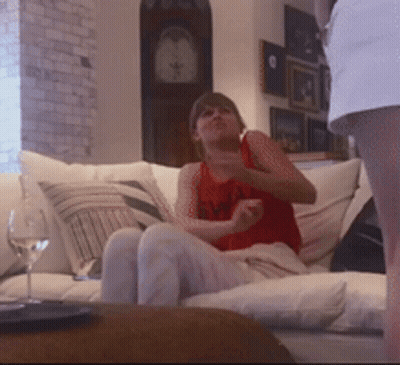 Woman In Red Tank Top Sitting On Couch With Clock GIF