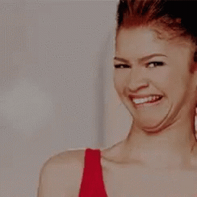 Woman In Red Tank Top Smiling And Looking Down GIF