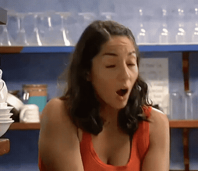 Woman In Red Tank Top Smiling In Front Of MTV Shelf GIF