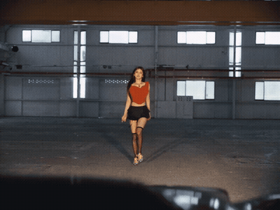 Woman In Red Top And Black Skirt Walking In Dark Room GIF