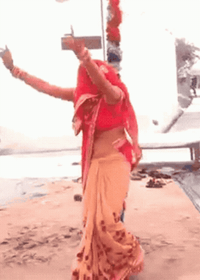 Woman In Red Top And Orange Skirt Dancing On Beach GIF