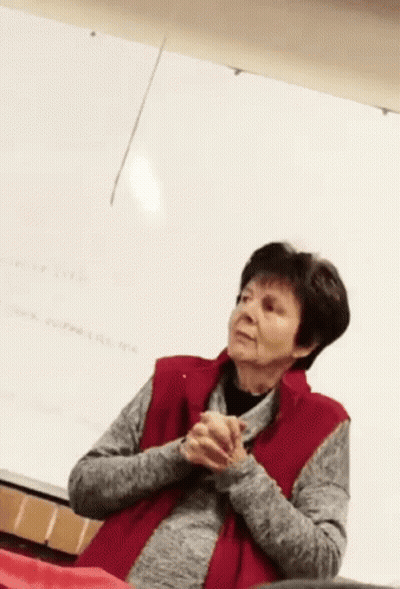 Woman In Red Vest Sitting In Front Of Whiteboard GIF