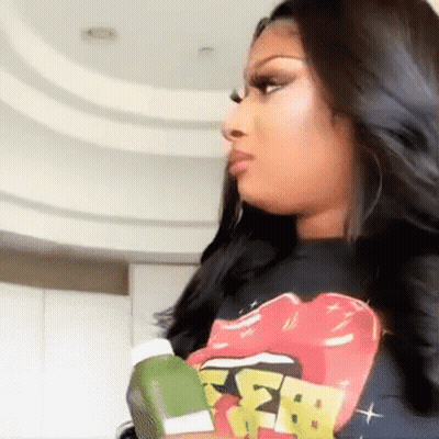 Woman In Rolling Stones T-Shirt Holding Green Object GIF