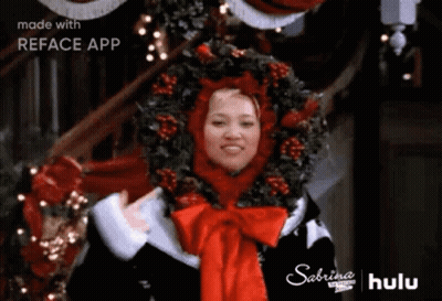 Woman In Santa Hat And Wreath With Christmas Tree GIF