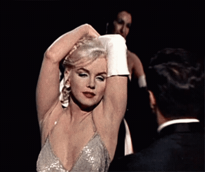Woman In Sequined Dress Adjusting Hair Next To Man In Tuxedo GIF