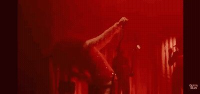Woman In Sheer Dress Singing Into Microphone On Stage GIF