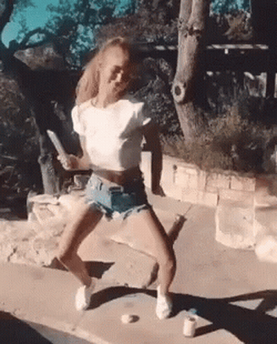 Woman In Shorts And White Crop Top Dancing On Sidewalk GIF