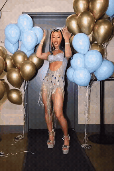 Woman In Silver Dress Dancing In Front Of Balloons GIF
