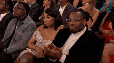 Woman In Silver Dress Next To Man In Suit In Crowd GIF