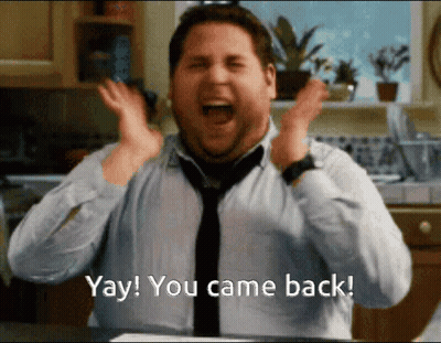 Woman In Silver Dress Saying Welcome Back GIF