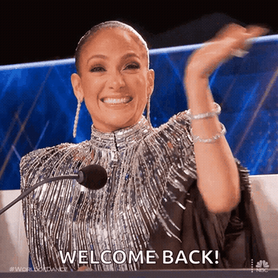 Woman In Silver Dress Saying Welcome Back GIF