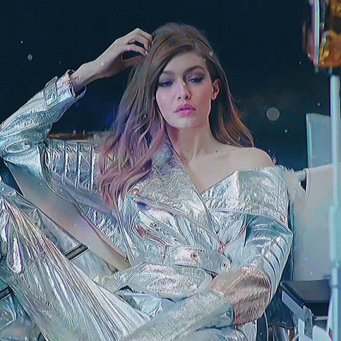 Woman In Silver Jacket And Pants Sitting GIF