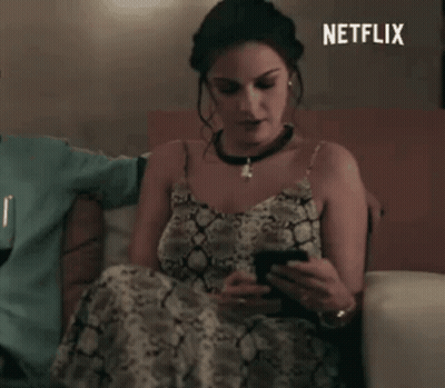 Woman In Snake Print Dress Looking At Phone On Couch Netflix GIF