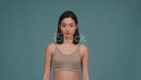 Mujer en sostén deportivo flexionando músculos GIF
