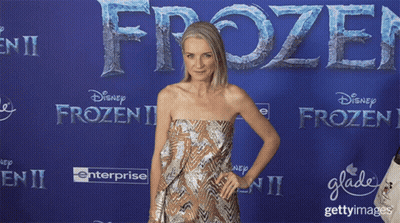 Woman In Strapless Dress In Front Of Blue Wall Saying Frozen II GIF