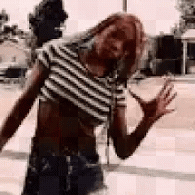 Woman In Striped Crop Top Standing On Sidewalk GIF