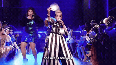 Woman In Striped Dress Holding Fan Singing Into Microphone GIF
